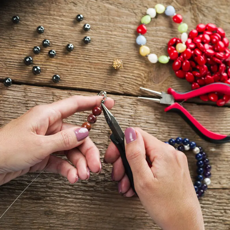 A person is making jewelry on the table.