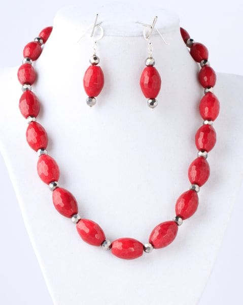 A red necklace and earrings set on a white bust.